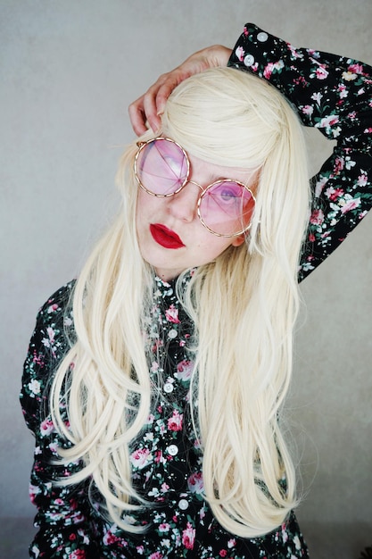 Photo woman with long blond hair wearing purple sunglasses against wall