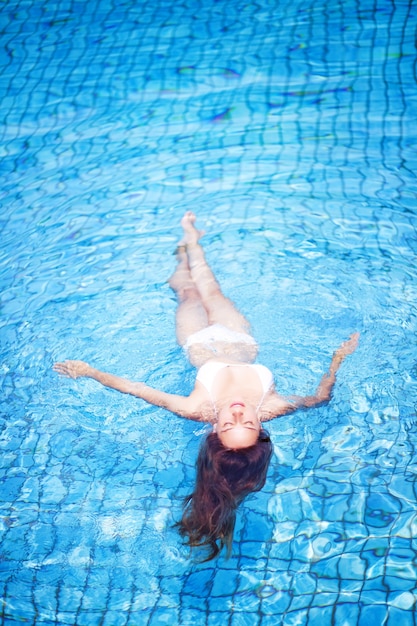 Woman with long hair floating in a pool