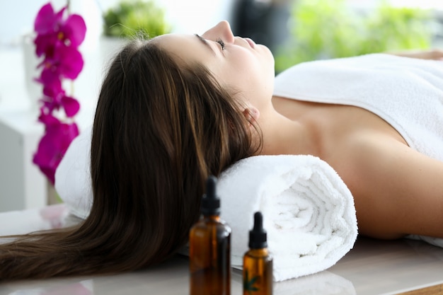 Woman with long hair lay on her back on massage table with her eyes closed.