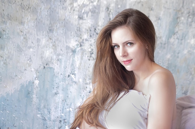 A woman with long hair and a white shirt is posing for a photo.