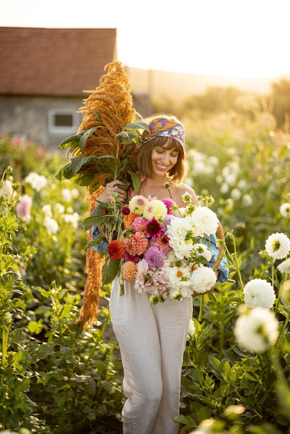 屋外のダリア農場にたくさんの花を持つ女性