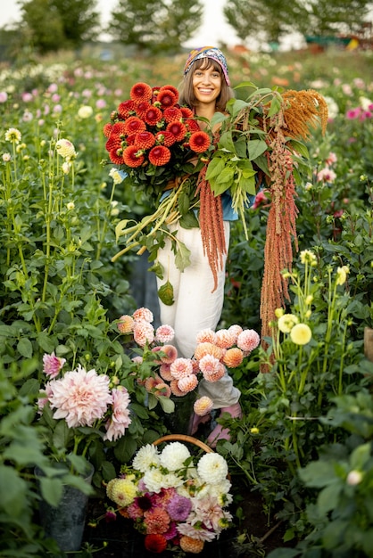 Woman with lots of flowers on dahlia farm outdoors