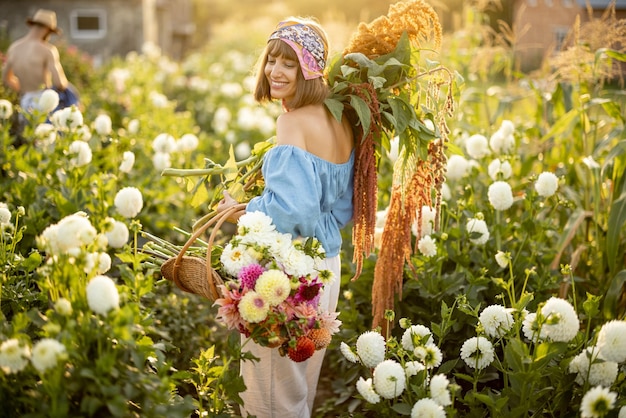 Woman with lots of flowers on dahlia farm outdoors