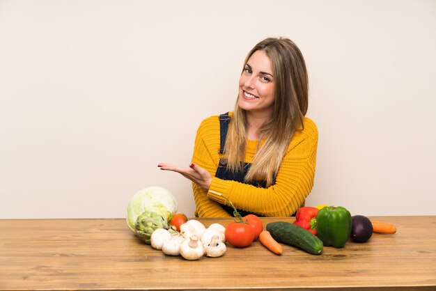 Woman with lots of vegetables extending hands to the side for inviting to come