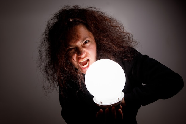 Photo woman with a luminous ball. demonic look