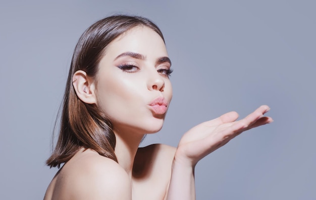 Woman with makeup blow air kiss Goodbye on distance isolated on grey background