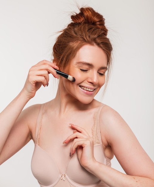 A woman with a makeup brush on her face