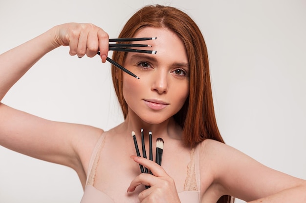 A woman with makeup brushes on her face