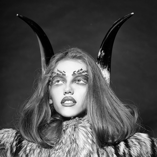 Женщина с макияжем в стиле демона Девушка с рогами и шубой