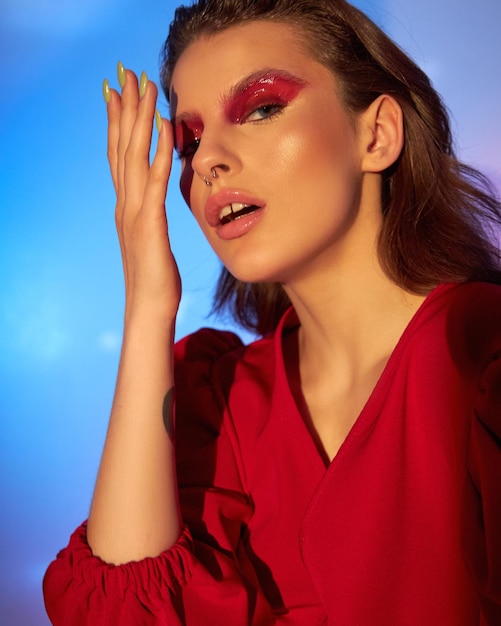 woman with makeup and wavy brunette hair in red silk dress in strip of light spot gobo light