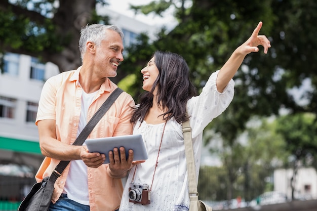 Donna con uomo che punta in città mentre si utilizza la tavoletta digitale