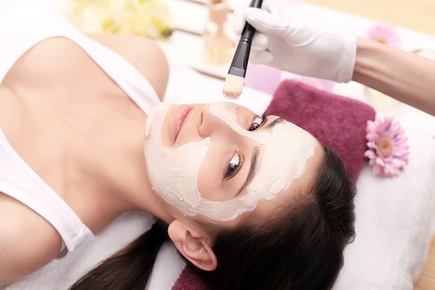 Donna con maschera sul viso con massaggio alla testa,