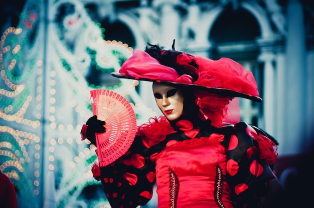 Foto donna con maschera che tiene in mano il ventilatore durante il carnevale