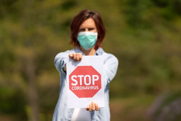 Woman with mask holding a sign