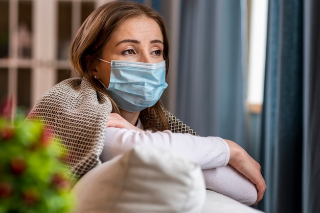 Foto donna con maschera rimanendo in quarantena guardando lontano