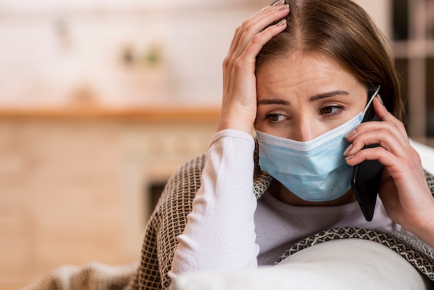 Foto donna con la maschera che resta nella quarantena che parla sul telefono