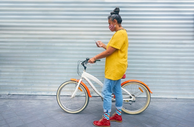 Woman with mask taking a bicycle for a ride in the city