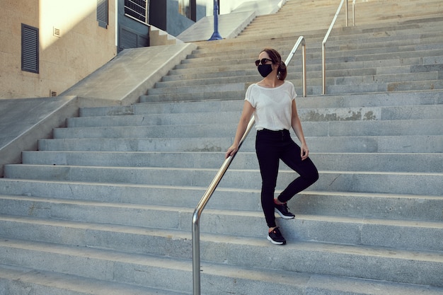 woman with mask walking down stairs in a city