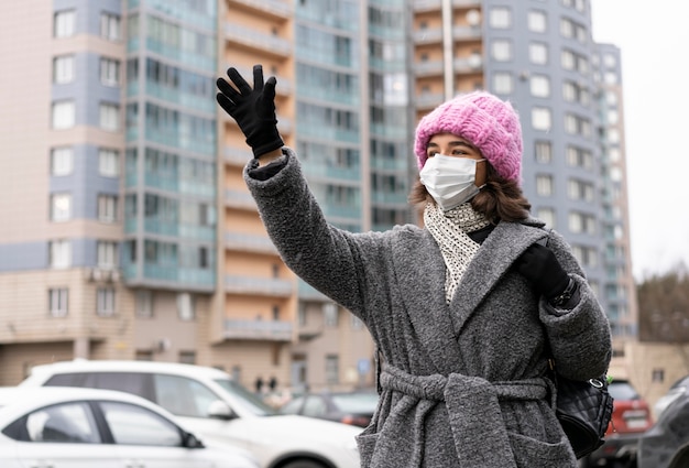 手を振っている街の医療マスクを持つ女性