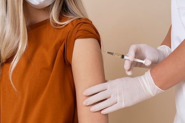 Женщина с медицинской маской получает вакцину