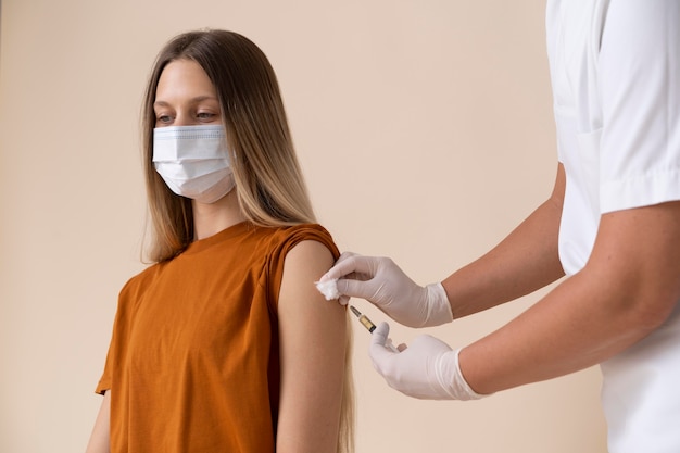 Woman with medical mask receiving a vaccine