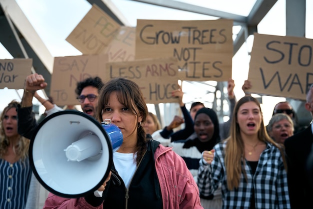 Woman with megaphone in protest group activist people demonstrate together shouting against wars