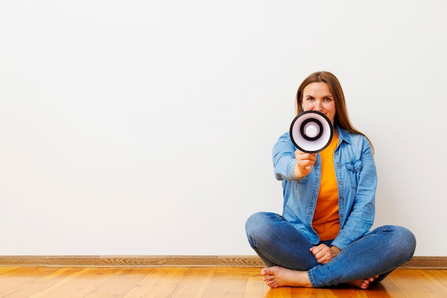 Woman with megaphone sitting on wooden floor