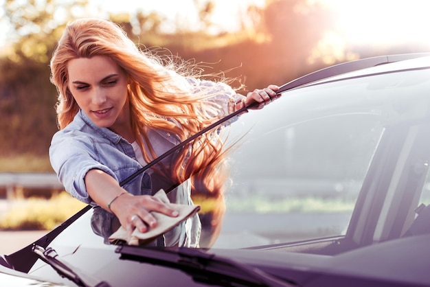 Woman with microfiber cloth cleaning car