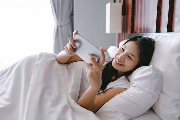 ベッドの上の携帯電話を持つ女性