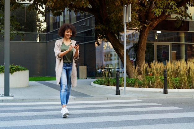 Woman with mobile phone crossing the street