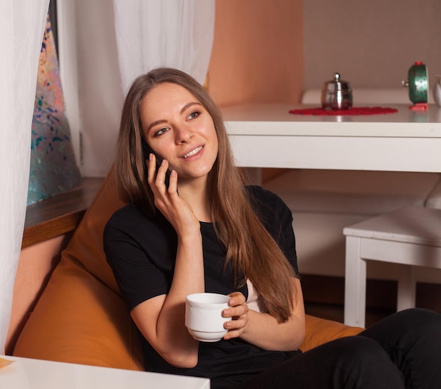 Woman with mobile phone and cup of coffee