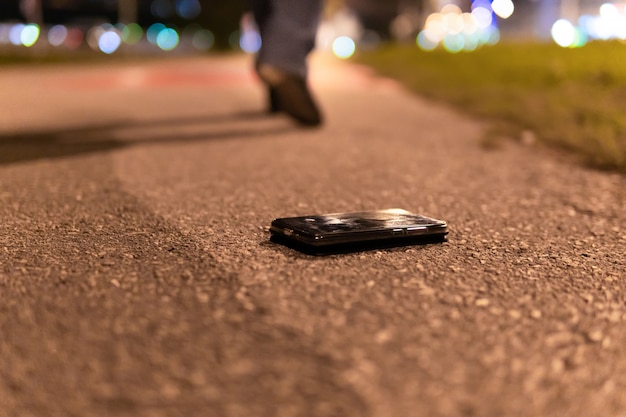 A woman with a mobile phone in her hand is walking through the night city.