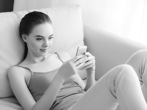Foto donna con telefono cellulare a casa sul divano utilizzando smartphone casual lifestyle femminile bellissimo modello ritratto