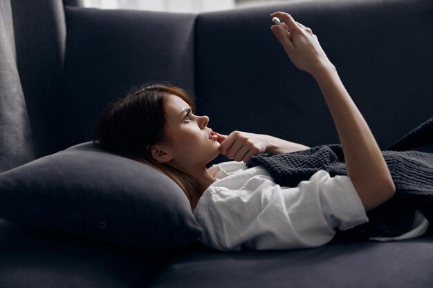 Woman with mobile phone lies on the sofa indoors interior Comfort