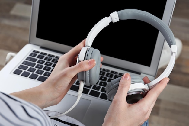 Photo woman with modern laptop and headphones sitting on floor concept of audiobook