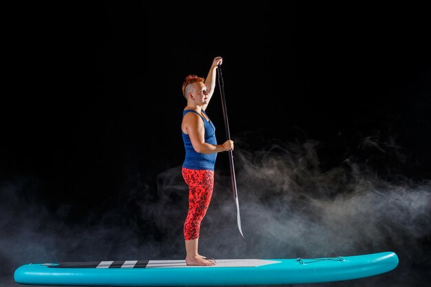 A woman with a mohawk on a snowboard in the fog on a black background