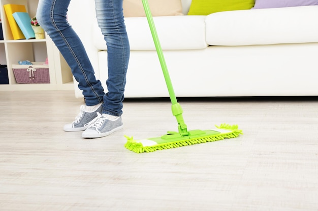 Woman with mop cleaning wooden floor from dust