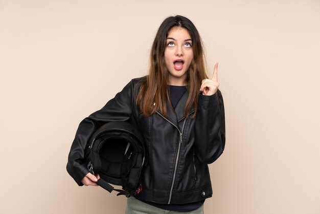 Woman with a motorcycle helmet on beige wall pointing with the index finger a great idea