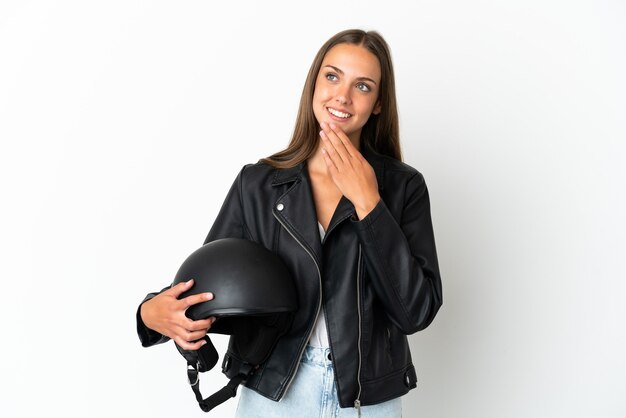 Woman with a motorcycle helmet over isolated white background looking up while smiling