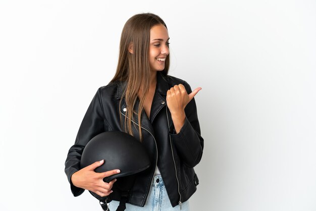 Woman with a motorcycle helmet over isolated white background pointing to the side to present a product