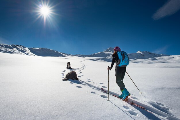 Woman with mountain skiing and two friends dogs