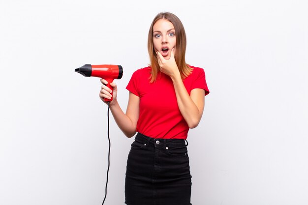 woman with mouth and eyes wide open and hand on chin, feeling unpleasantly shocked, saying what or wow