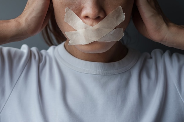 Donna con la bocca sigillata con nastro adesivo. libertà di parola, libertà di stampa, diritti umani, dittatura di protesta, democrazia, libertà, uguaglianza e concetti di fraternità