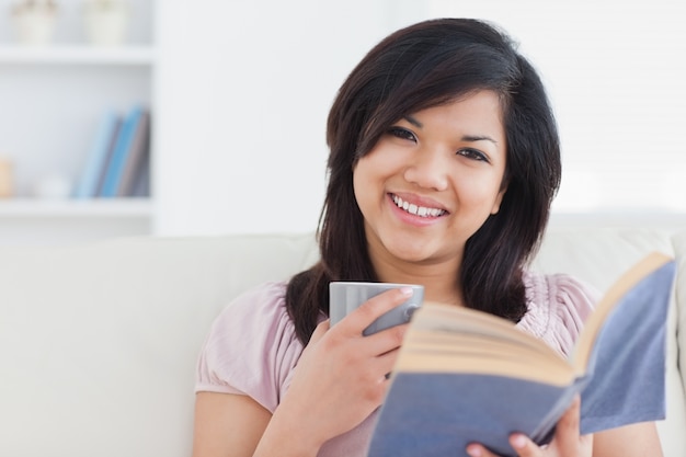 Donna con una tazza e un libro tra le mani