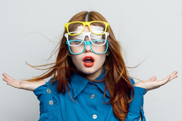 Woman with multicolored glasses on her face in blue shirt posing glamor