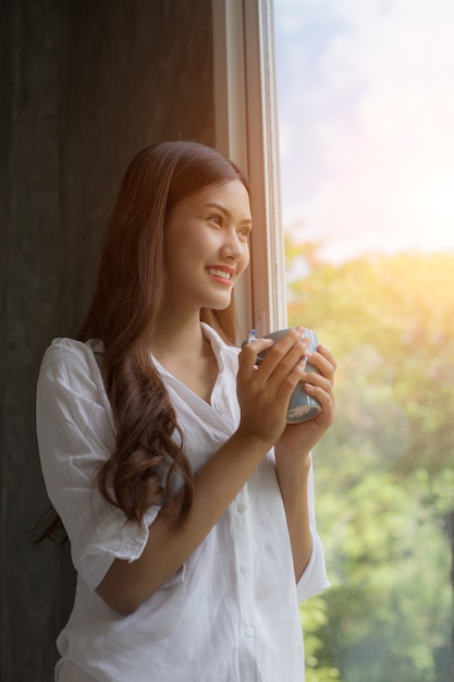 woman with neat body is holding a cup with hot tea or coffee 