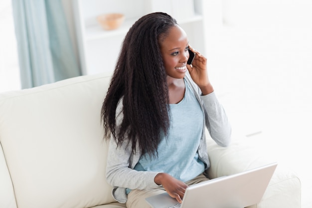 Woman with notebook and smartphone on the sofa