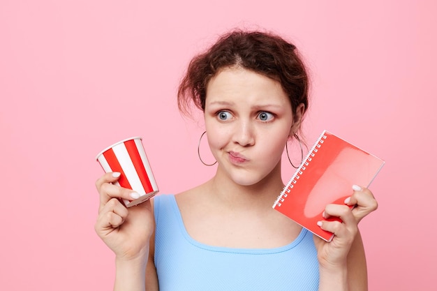 Woman with notepad and glass in hands drink pink background unaltered