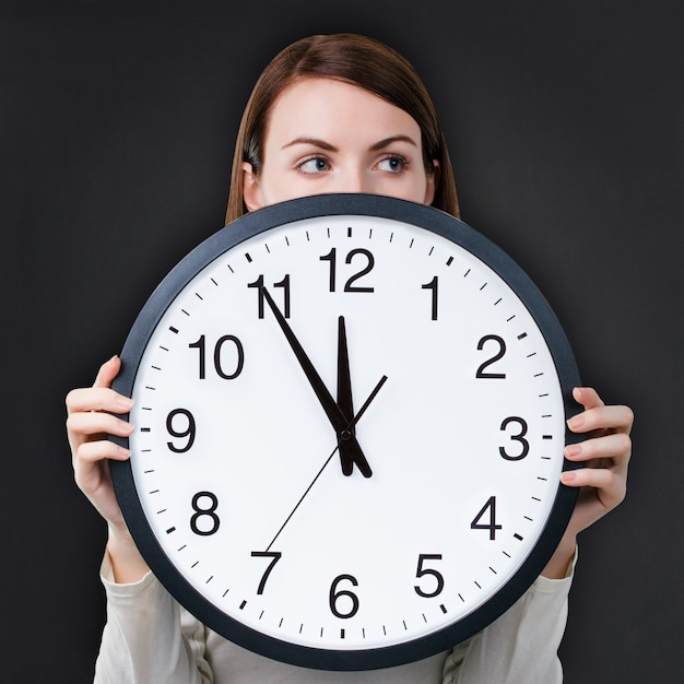 Woman with an office clock against chalkboard background