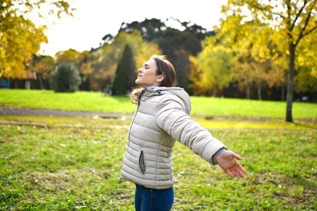 写真 秋または冬の茂みや野原で、両手を広げて新鮮なきれいな空気を呼吸する女性